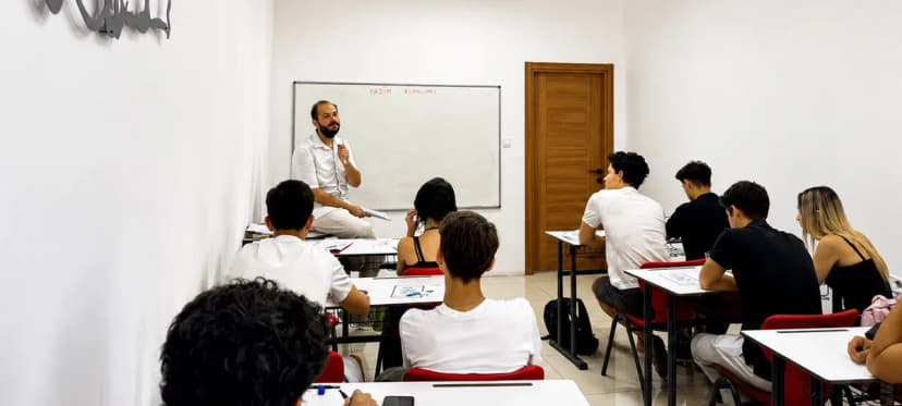 KITA'da ders anı: öğretmen tahtanın önünde anlatıyor, öğrenciler not alıyor